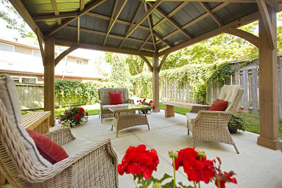 a covered patio with wicker furniture and red flowers