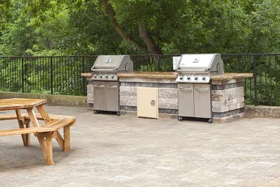 an outdoor kitchen with two grills and a picnic table