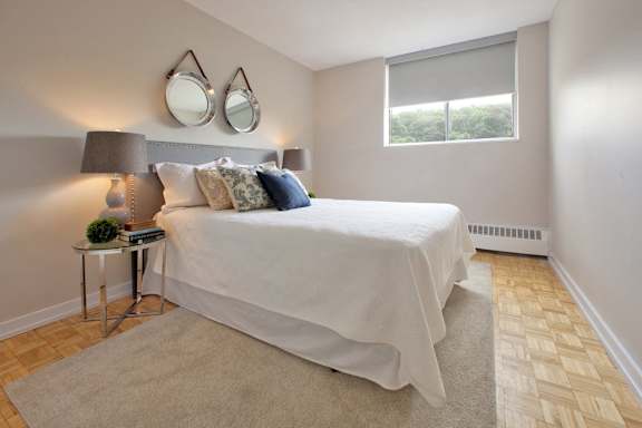 a bedroom with a white bed and two mirrors on the wall