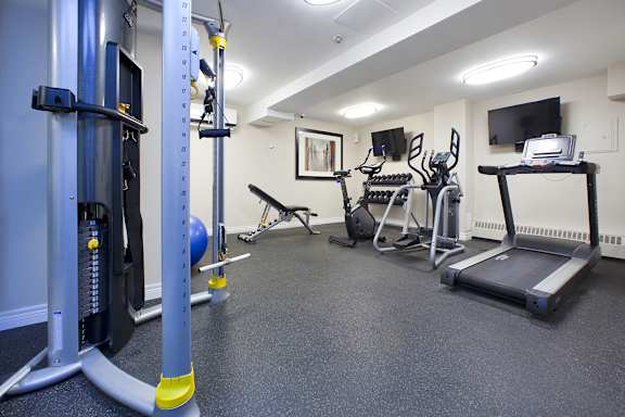 a gym with cardio equipment and weights on the floor and a tv