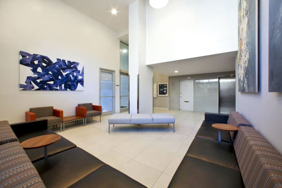 a lobby with couches and chairs and a blue abstract painting on the wall