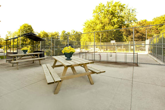 a picnic table in a park next to a tennis court