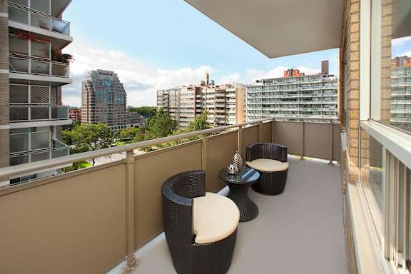 a balcony with two chairs and a table and a view of the city