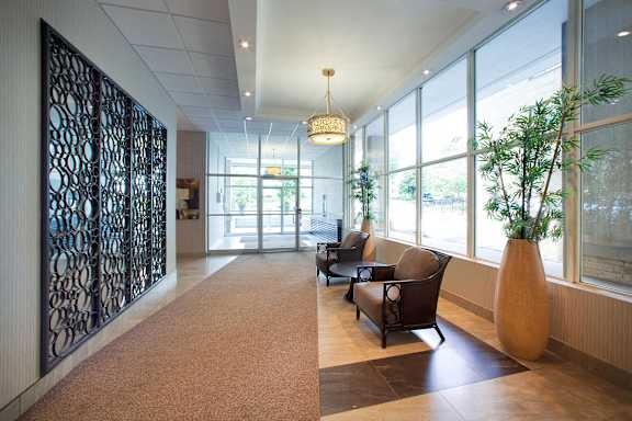 a large hallway with chairs and plants in a lobby of a building
