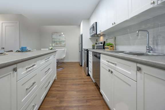 a long kitchen with white cabinets and stainless steel appliances