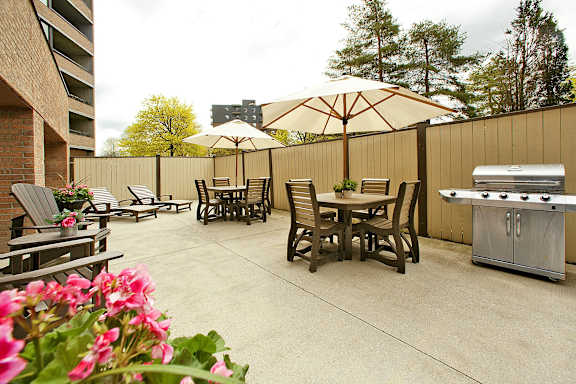 a patio with a grill and tables with umbrellas