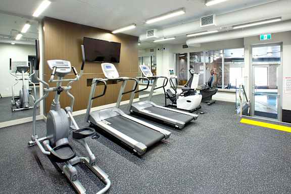 a gym with cardio equipment and a tv