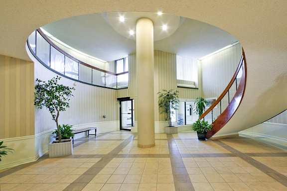 a large lobby with a large spiral staircase and plants