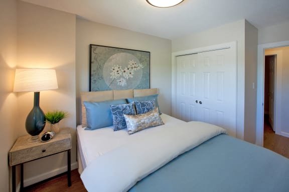a bedroom with a bed with blue pillows and a night stand with a lamp