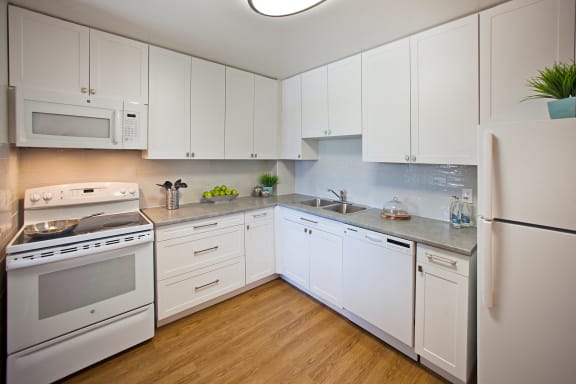 a kitchen with white cabinets and appliances and a white refrigerator