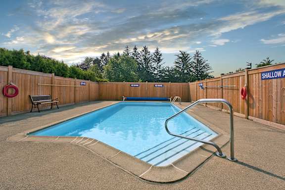 a swimming pool in a backyard with a fence and a bench