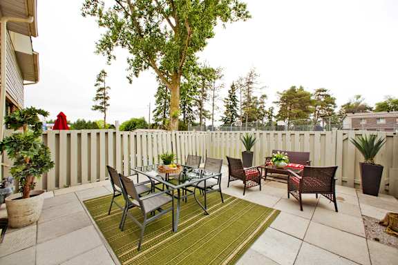 a patio with a table and chairs in front of a white fence