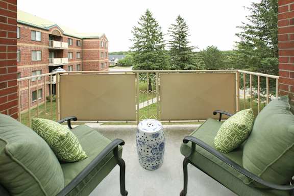 a balcony with two chairs and a table with pillows on it