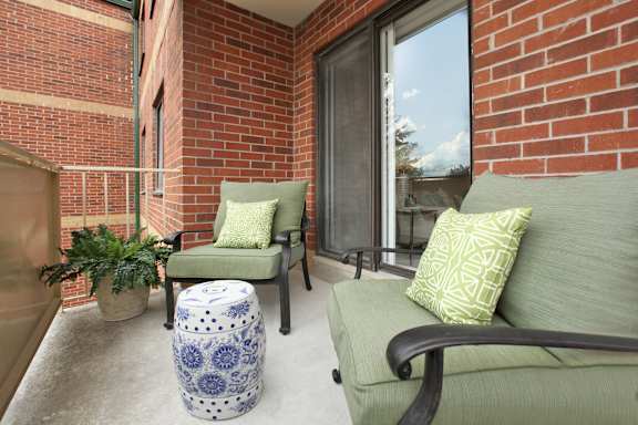 a balcony with a couch and chairs and a brick wall