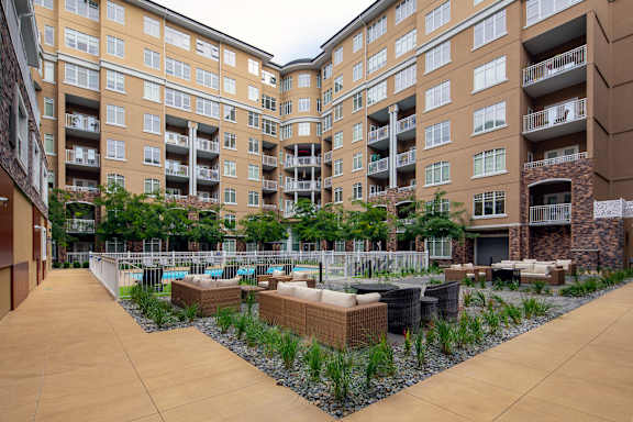 an outdoor area with seating and plants in front of an apartment building