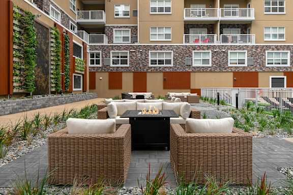 a patio with chairs and a table in front of an apartment building