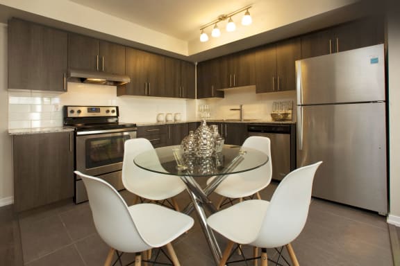 a kitchen with stainless steel appliances and a glass table with white chairs