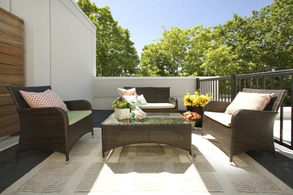 a patio with chairs and a table with flowers on it