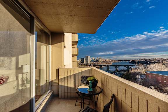 a balcony with a table and chairs and a view of the city