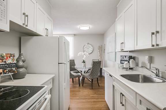 a kitchen with white cabinets and white appliances and a dining room table