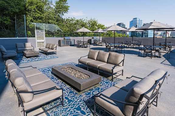 a rooftop lounge area with couches tables and chairs and umbrellas