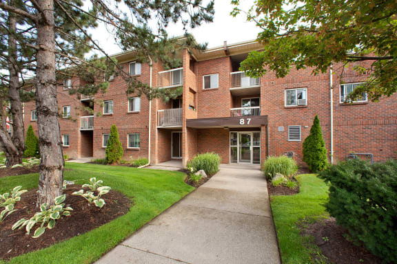 a sidewalk in front of a brick apartment building