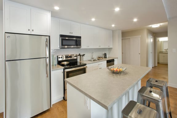 a large kitchen with white cabinets and stainless steel appliances