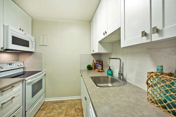 a kitchen with white cabinets and appliances and a sink