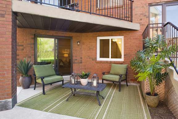 a patio with chairs and a table in front of a brick house