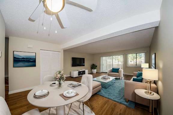 a living room with a table and a ceiling fan