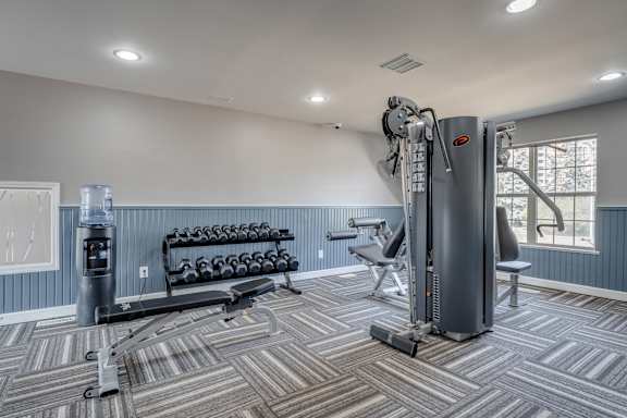 A gym with a variety of equipment including a treadmill, weights, and a bench.