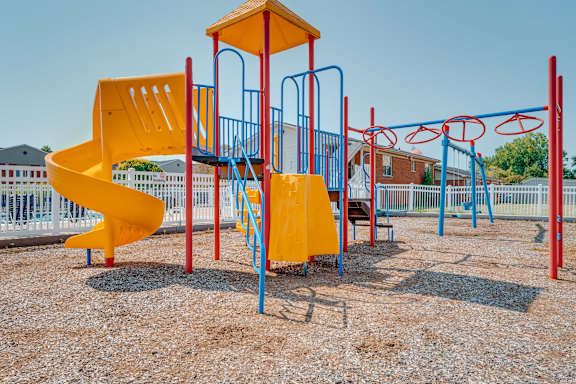 A playground with a yellow slide and blue and red structures.