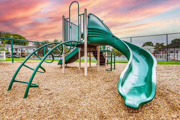 A playground with a green slide and a climbing frame.
