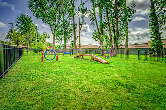 A playground with a green lawn and a black fence.