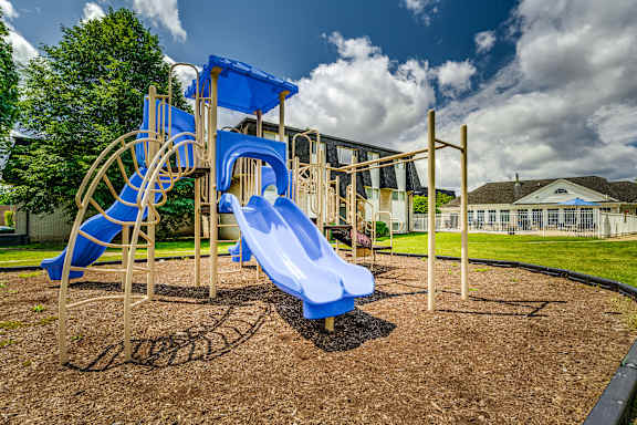 A playground with a blue slide and a wooden structure.