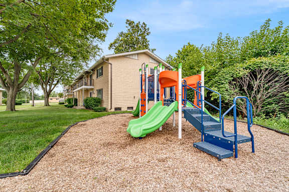 A playground with a green slide and a blue staircase.