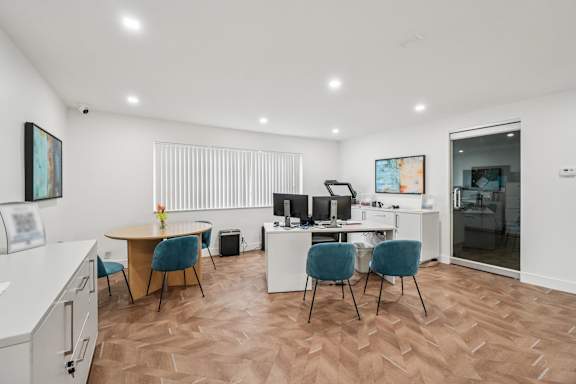 A room with a desk, chairs, and a computer setup.