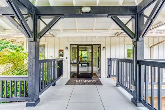 A covered walkway with a metal railing and a brown doormat that says "Yale".
