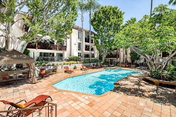 A pool surrounded by trees and chairs.