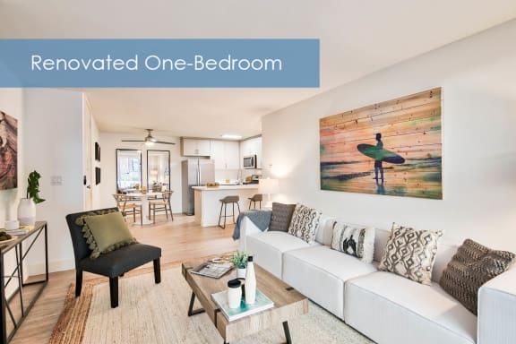 a renovated one bedroom living room with a white couch and a surfboard at The Meadows Apartments, Culver City , CA 90230