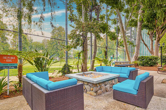 a patio with blue chairs and a fire pit
