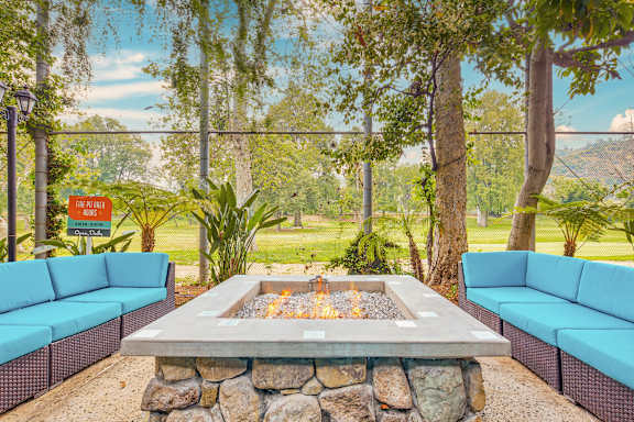 a fire pit with two blue couches and a stone wall