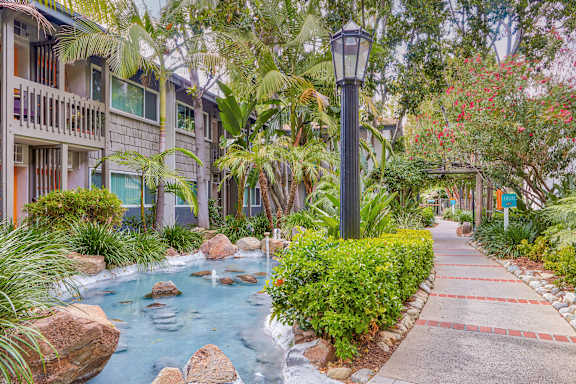 a sidewalk with a water feature in front of a building