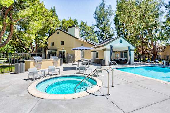 A pool with a hot tub and a house in the background.