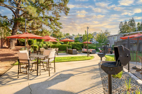 a patio with tables and umbrellas and a grill