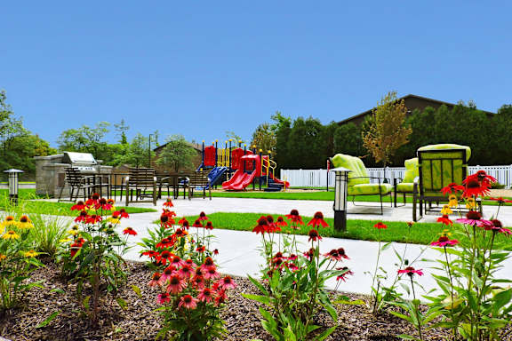 A playground with a red slide and green chairs.
