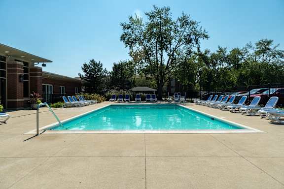A large swimming pool surrounded by chairs and trees.