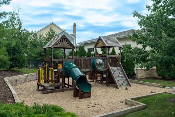 A playground with a green slide and a yellow swing set.