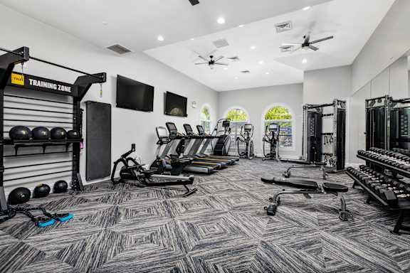 A gym with a variety of equipment including weights, treadmills, and exercise machines.