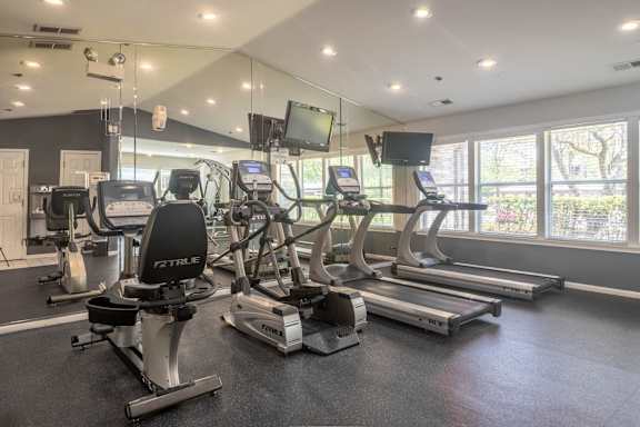 A gym with treadmills, stationary bikes, and elliptical machines.